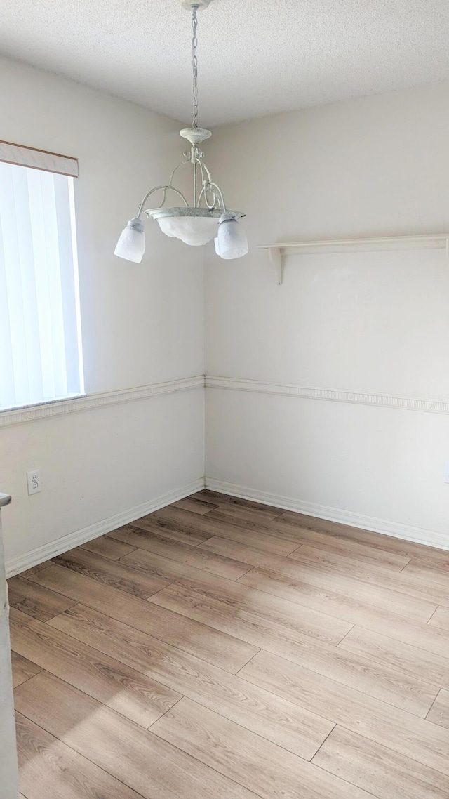 unfurnished dining area featuring light hardwood / wood-style flooring and a textured ceiling