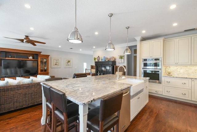 kitchen with dark hardwood / wood-style floors, appliances with stainless steel finishes, sink, and ceiling fan