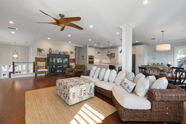 living room with decorative columns, sink, ceiling fan, wood-type flooring, and ornamental molding