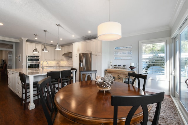 dining space featuring ornamental molding, sink, and dark wood-type flooring