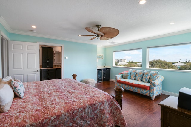 bedroom with dark wood-type flooring, beverage cooler, ceiling fan, ensuite bathroom, and ornamental molding