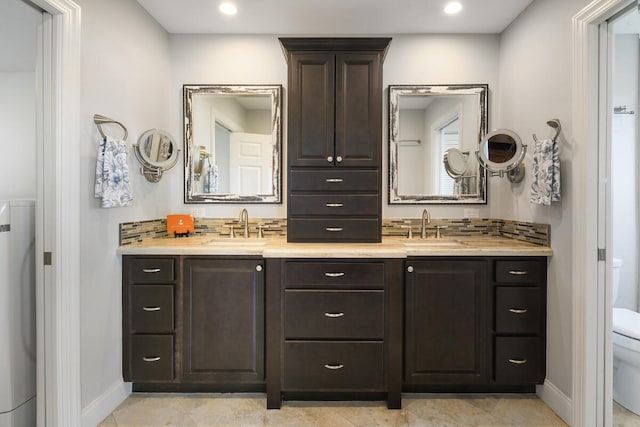 bathroom featuring toilet, tile patterned flooring, and dual bowl vanity