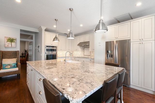 kitchen featuring stainless steel appliances, pendant lighting, sink, dark hardwood / wood-style floors, and a center island with sink