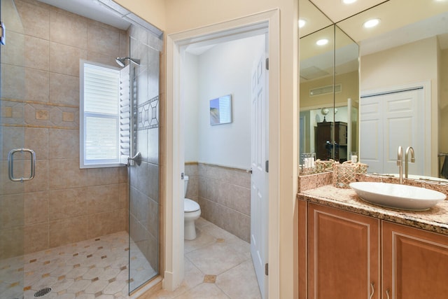 bathroom with a shower with shower door, vanity, tile patterned flooring, and toilet