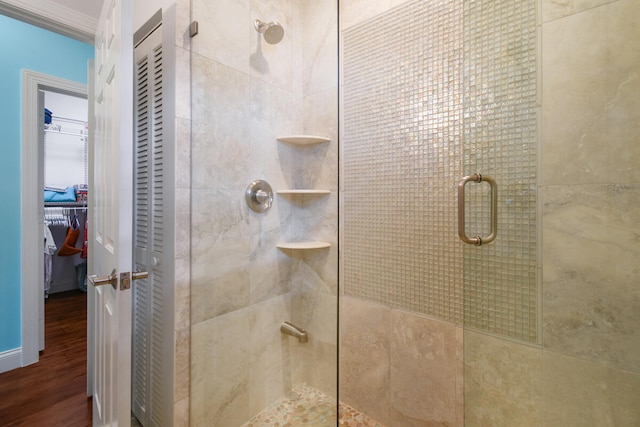 bathroom featuring a shower with shower door, crown molding, and hardwood / wood-style floors