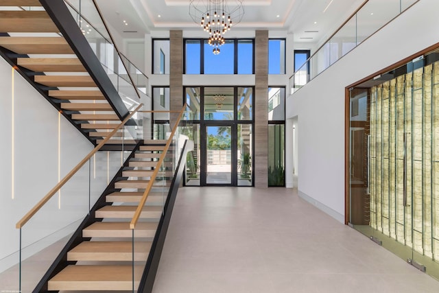 entryway with a high ceiling, a tray ceiling, and an inviting chandelier