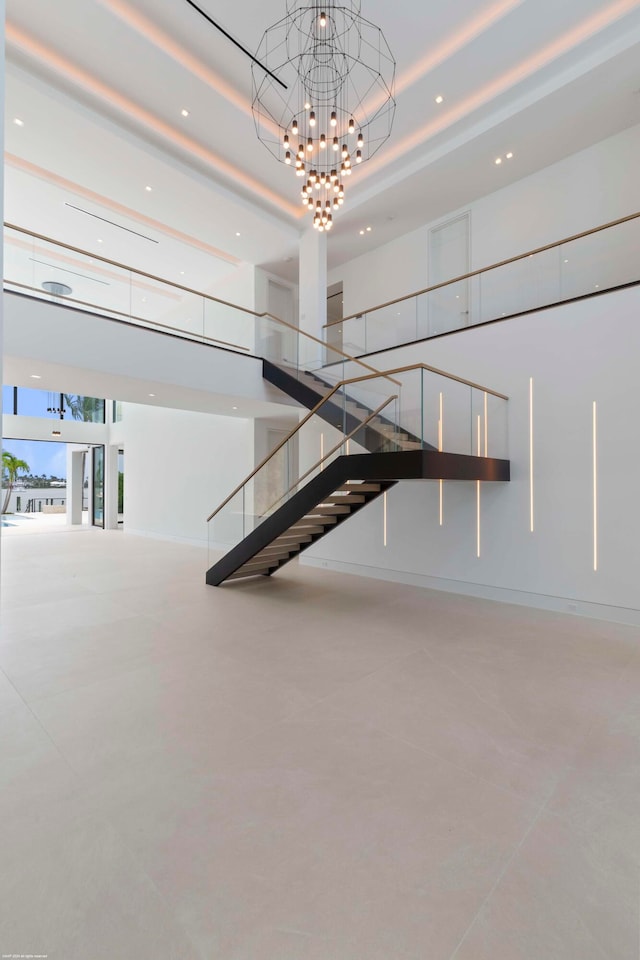 stairs with concrete floors, a towering ceiling, and an inviting chandelier