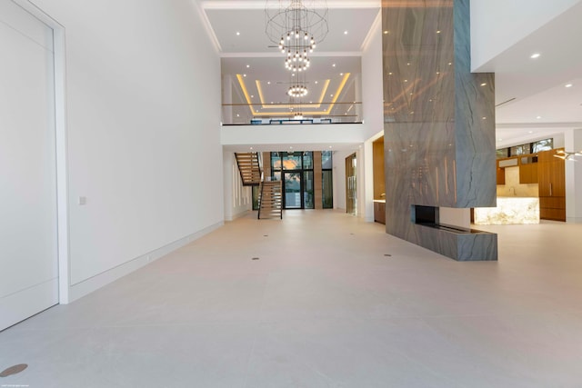 unfurnished living room featuring a multi sided fireplace, a chandelier, concrete flooring, and a towering ceiling