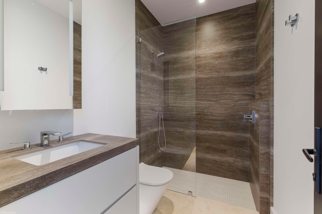 bathroom with toilet, tile patterned flooring, vanity, and tiled shower