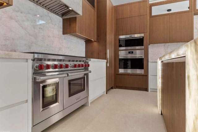 kitchen with stainless steel appliances, tasteful backsplash, light tile patterned flooring, and premium range hood