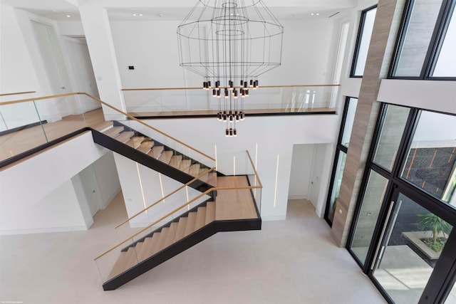 stairway featuring a towering ceiling and an inviting chandelier