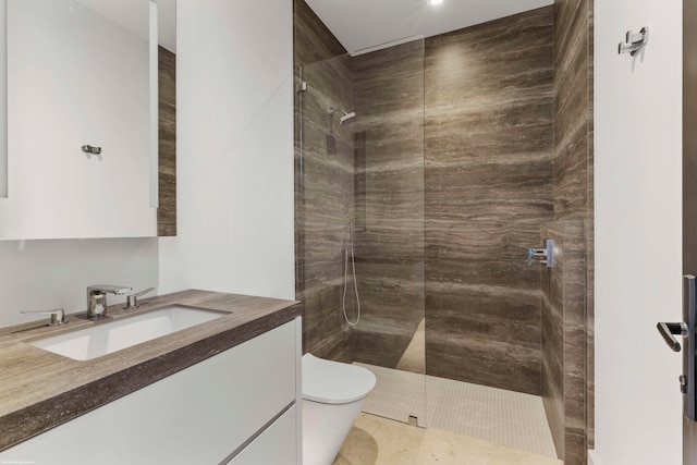 bathroom with vanity, a tile shower, toilet, and tile patterned flooring