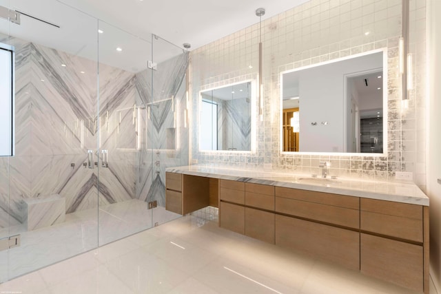 bathroom with decorative backsplash, tile walls, a shower with shower door, vanity, and tile patterned floors