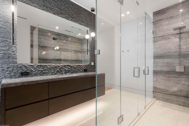 bathroom featuring vanity, tasteful backsplash, tile walls, and a shower with door