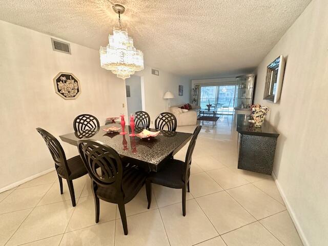 tiled dining space with a chandelier and a textured ceiling