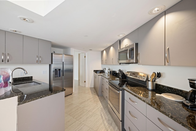 kitchen featuring gray cabinets, stainless steel appliances, dark stone countertops, sink, and light tile floors