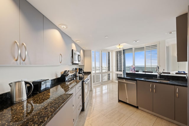 kitchen featuring appliances with stainless steel finishes, dark stone counters, white cabinetry, sink, and light tile floors