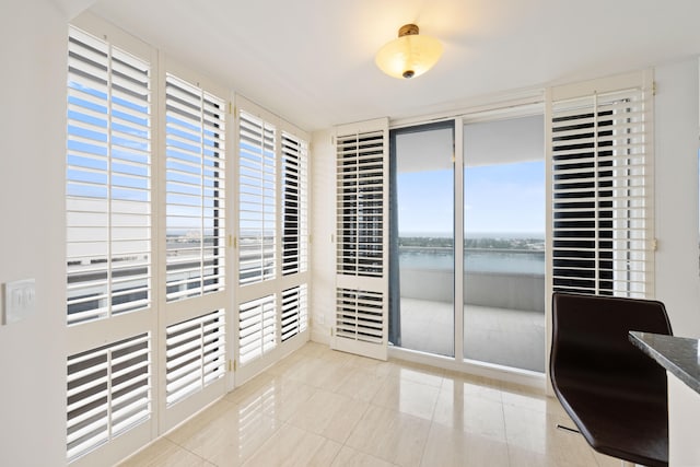 spare room with a water view, light tile floors, and a wealth of natural light