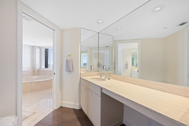 bathroom with large vanity and tiled tub