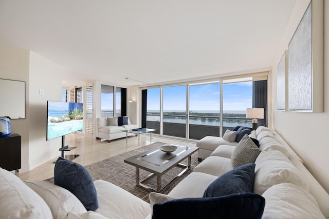 living room featuring tile floors, a wall of windows, and a water view