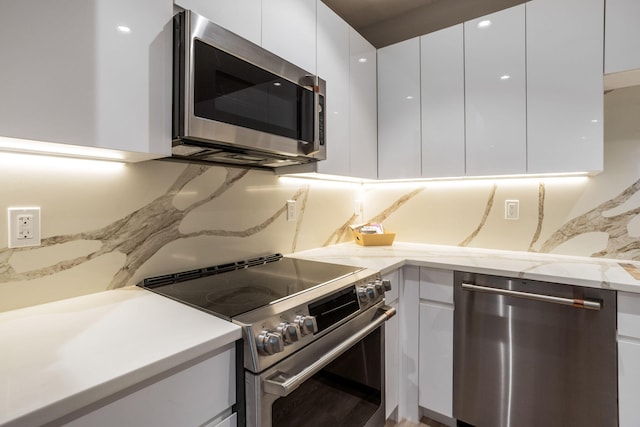 kitchen with white cabinetry, light stone countertops, stainless steel appliances, and decorative backsplash