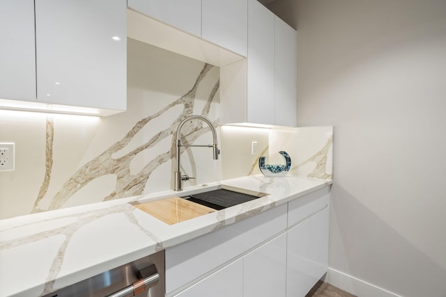 kitchen with sink, light stone countertops, and white cabinets