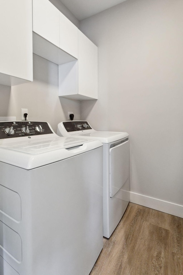 laundry room featuring cabinets, separate washer and dryer, and hardwood / wood-style floors