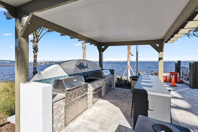 view of patio with exterior kitchen, a water view, and area for grilling