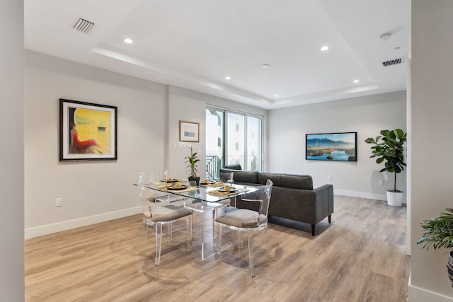 living room with light wood-type flooring and a raised ceiling