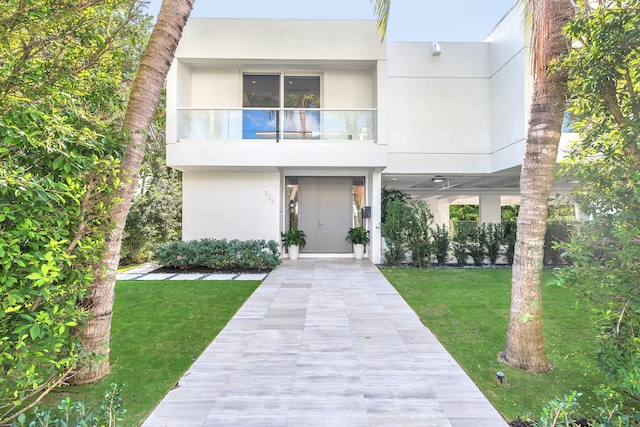 view of front of house with a balcony and a front lawn