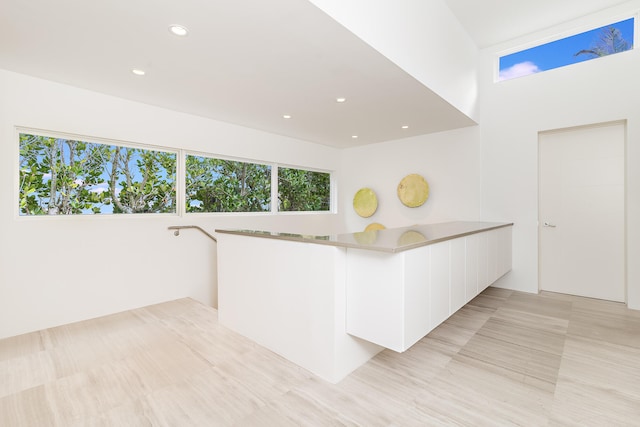 kitchen featuring kitchen peninsula, light tile patterned flooring, and white cabinetry