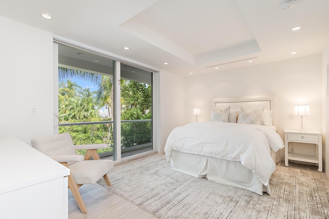 bedroom with a tray ceiling, a wall of windows, and recessed lighting