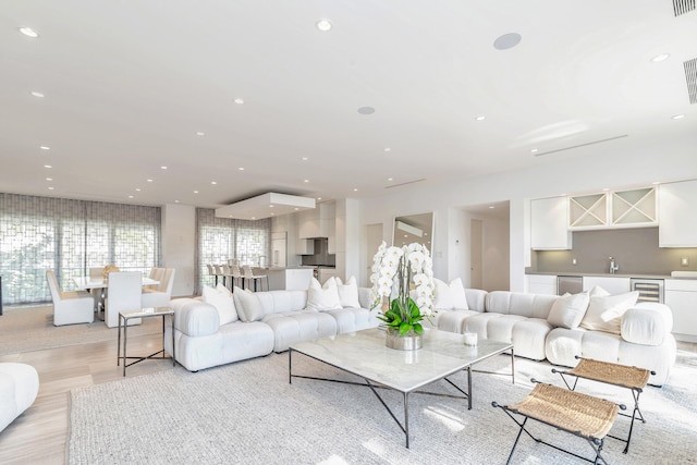 living room with light hardwood / wood-style floors, wine cooler, and sink