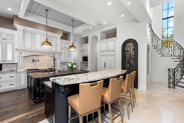 kitchen with a breakfast bar, tasteful backsplash, a spacious island, hanging light fixtures, and light hardwood / wood-style flooring