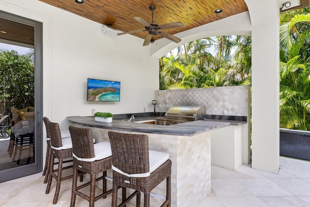 view of patio / terrace with a grill, ceiling fan, a bar, and exterior kitchen