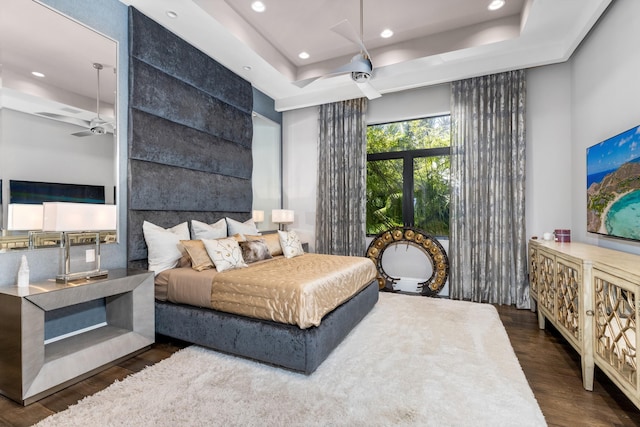 bedroom with dark hardwood / wood-style floors and a raised ceiling