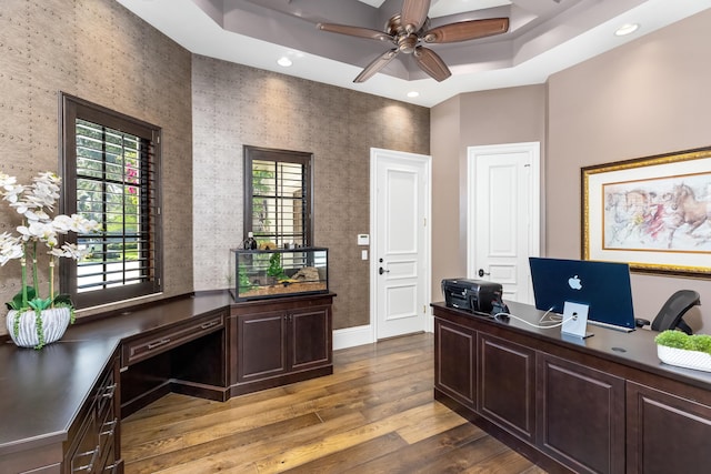 office featuring light hardwood / wood-style floors, ceiling fan, and a raised ceiling