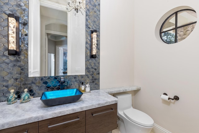 bathroom with backsplash, toilet, and vanity with extensive cabinet space