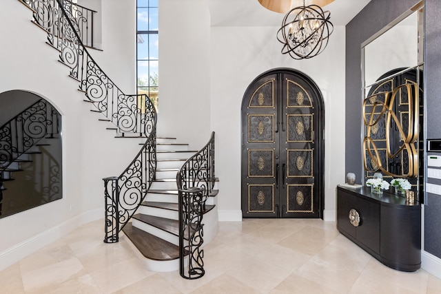 tiled foyer entrance featuring french doors, a notable chandelier, and a high ceiling