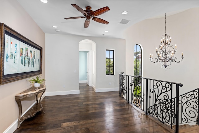 corridor featuring lofted ceiling, dark wood-type flooring, and a notable chandelier