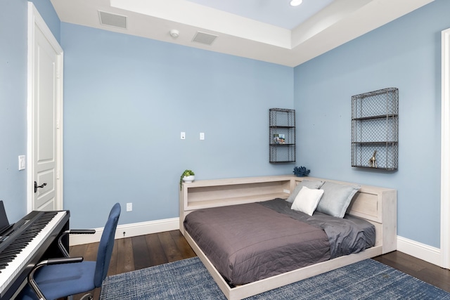 bedroom with dark hardwood / wood-style floors and a raised ceiling