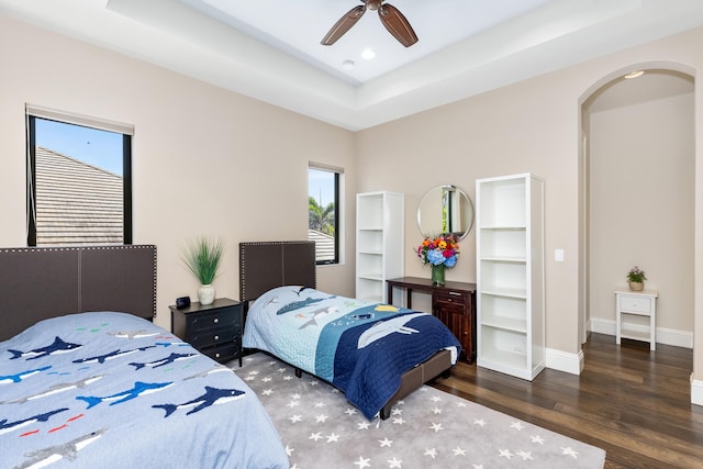 bedroom featuring dark hardwood / wood-style flooring, ceiling fan, and a raised ceiling