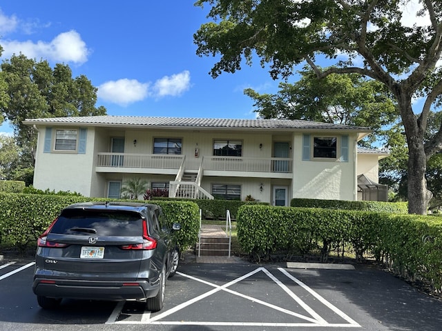 view of property with stairway and uncovered parking