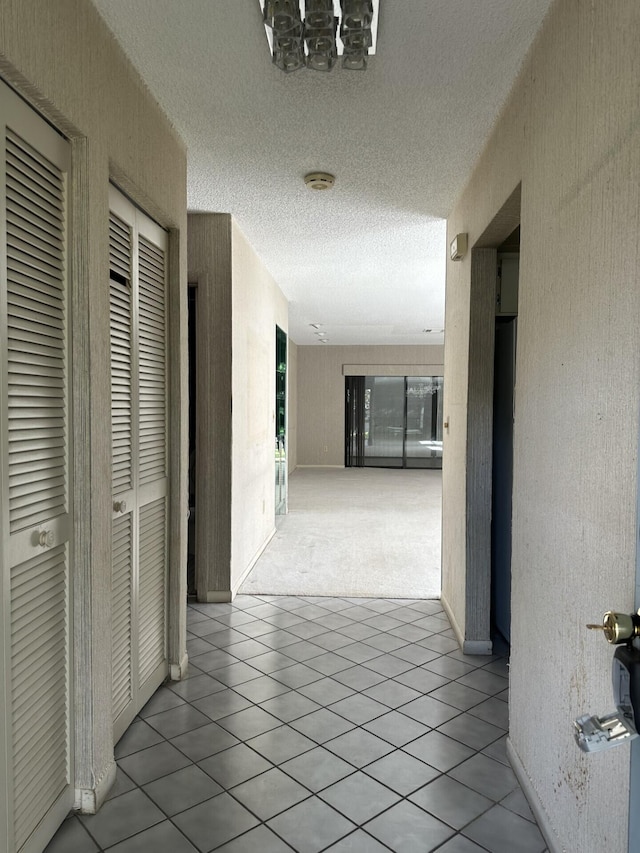 corridor featuring a textured ceiling and light tile patterned floors