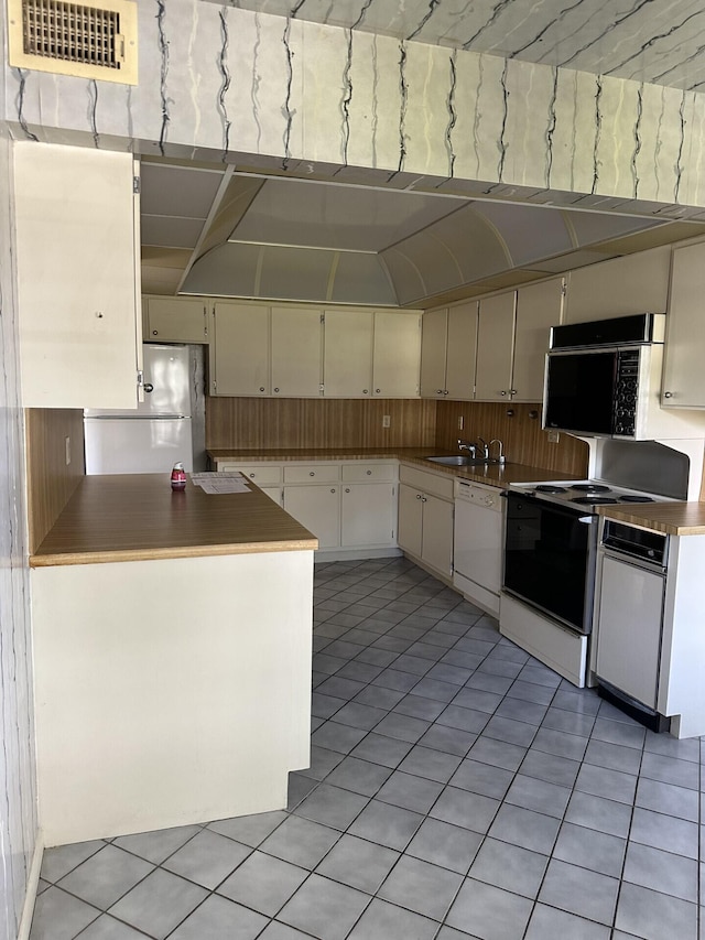 kitchen featuring visible vents, a sink, white cabinetry, white appliances, and light tile patterned flooring