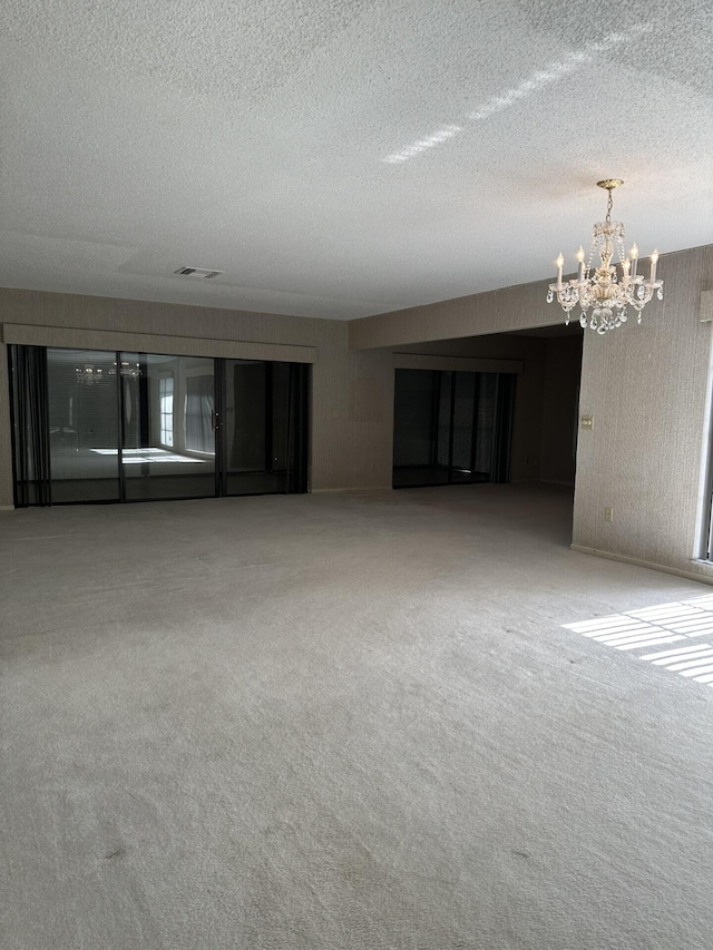 unfurnished living room featuring a textured ceiling, light colored carpet, and a chandelier