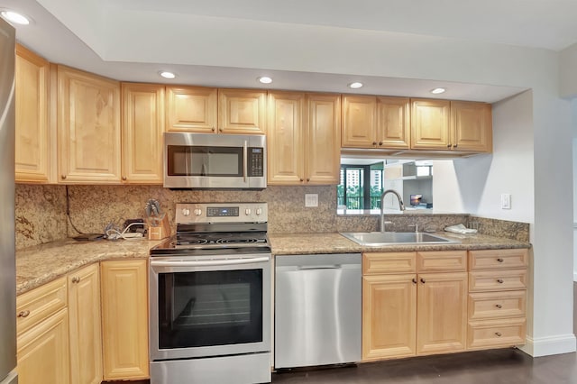 kitchen with light brown cabinetry, stainless steel appliances, and sink