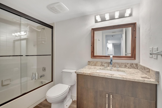 full bathroom with combined bath / shower with glass door, vanity, hardwood / wood-style flooring, and toilet