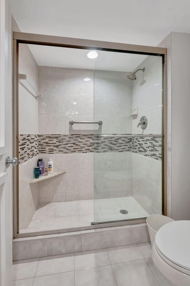 bathroom featuring tile patterned floors, toilet, and an enclosed shower