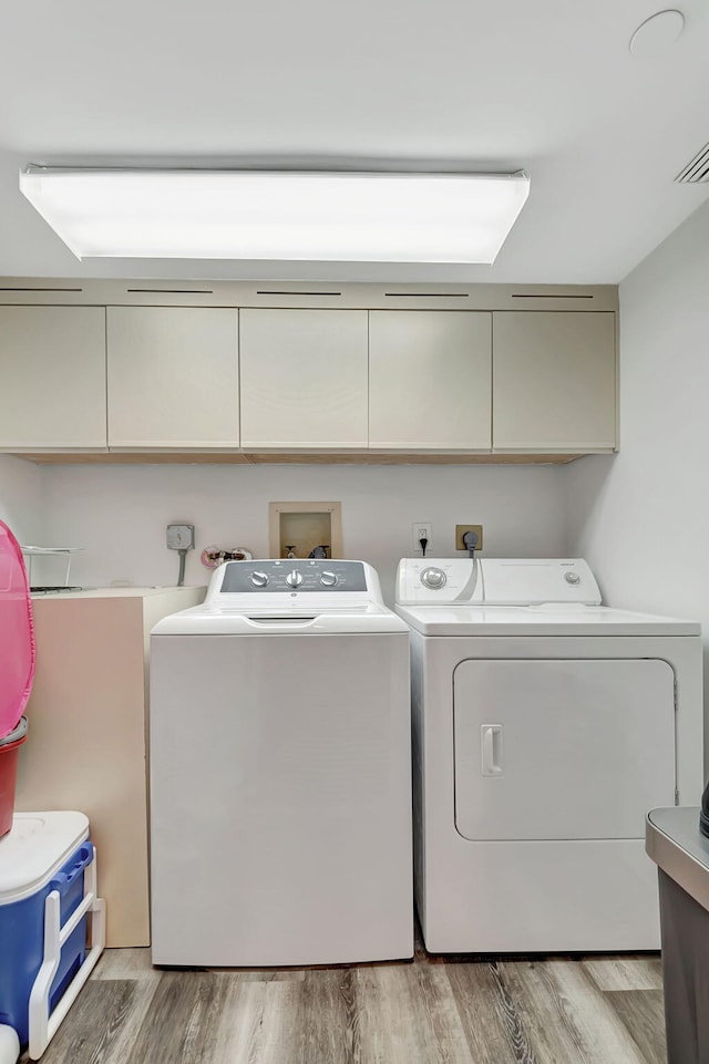 washroom with washer and dryer, cabinets, and wood-type flooring